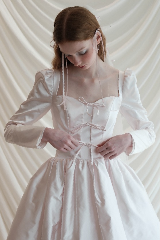 A bride ties a bow on her Marrow gown