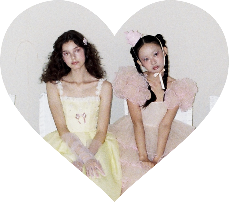 Two models in Puella Aeterna bridal gowns, framed by a heart